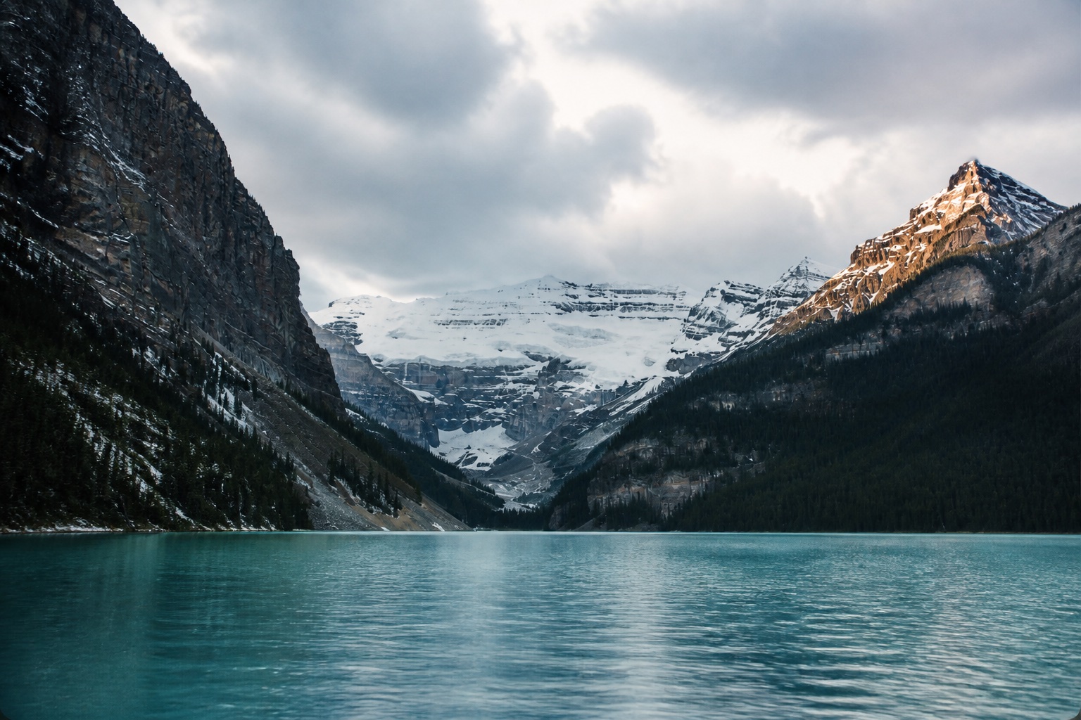A turquoise alpine lake surrounded by snow-covered mountains